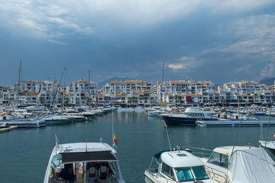 Sailboats moored at harbor against sky