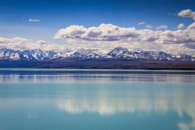 Reflection of snowcapped mountains in lake against cloudy sky