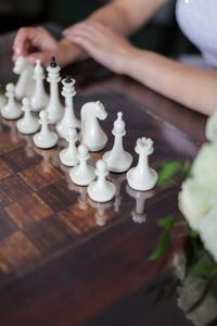 High angle view of woman sitting by chess board on table at home