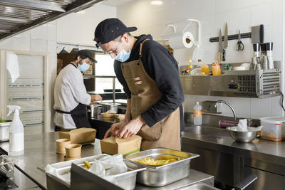 Chefs preparing takeaway food in kitchen at restaurant