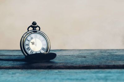 Close-up of clock on table against wall