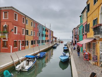 Boats moored on canal amidst buildings in city