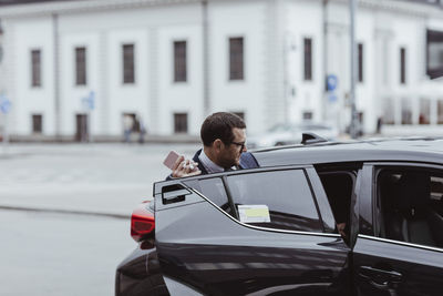 Businessman with smart phone sitting in car