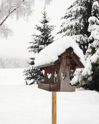 Snow covered wooden post on field during winter