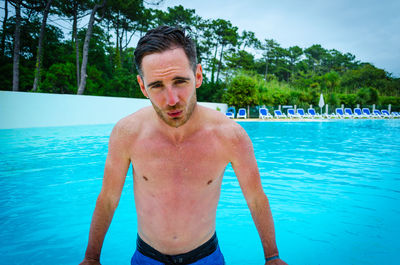 Portrait of wet man standing by swimming pool