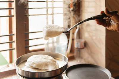 Idli or idly, savory rice cake from india, breakfast foods on south. woman cooking at home, hot food