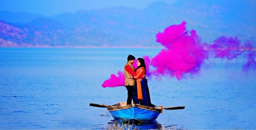 Woman standing on pink umbrella against sky