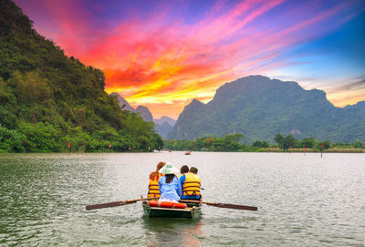 Rear view of man on boat in lake against sky