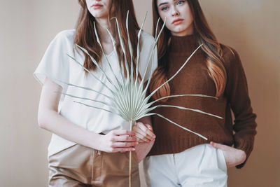 Midsection of females holding decoration standing against beige background