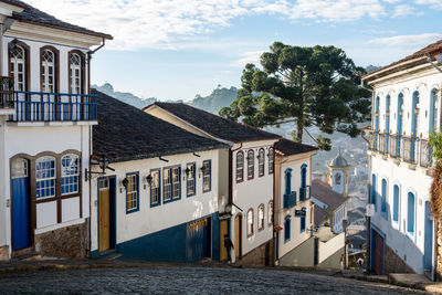 Houses by buildings in town against sky