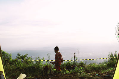 Rear view of man looking at plants against sky