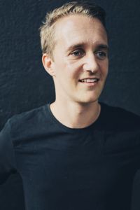 Portrait of young man standing against black background