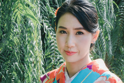 Close-up portrait of young woman standing by plants at park