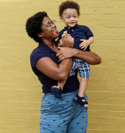 Happy family standing against wall