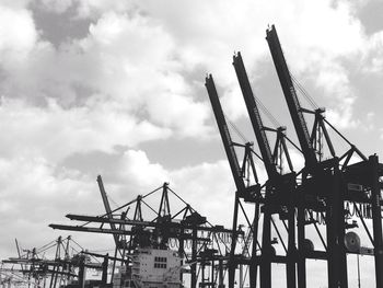 Low angle view of crane against cloudy sky