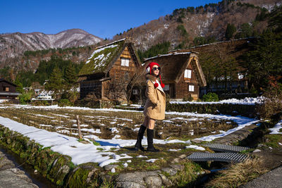 Full length of person standing on snow covered field against sky