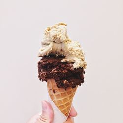 Close-up of hand holding ice cream against wall