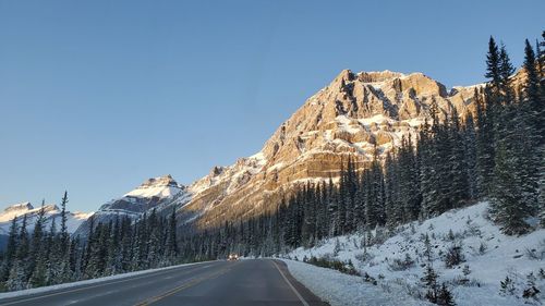 Road by snowcapped mountains against sky