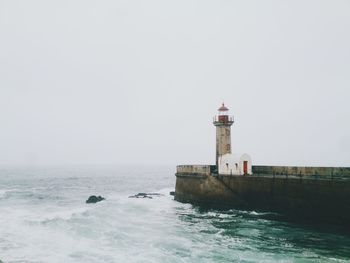 Lighthouse by sea against sky