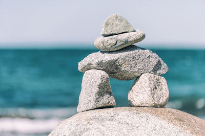 Close-up of stone stack on rock at beach against sky