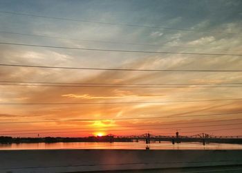 Bridge over river against orange sky