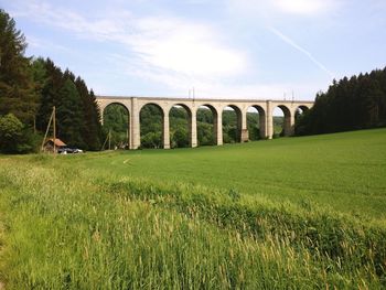 Arch bridge on field against sky