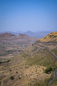 Scenic view of arid landscape against clear blue sky