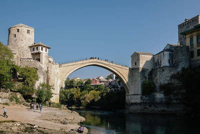 Arch bridge over river against clear sky