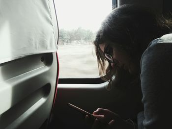 Side view of woman using mobile phone while sitting in train