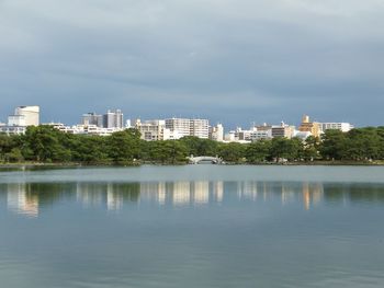 Buildings by lake against sky in city