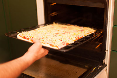 Close-up of woman preparing food in oven