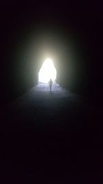 Silhouette woman in illuminated tunnel at night