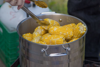 Close-up of person preparing corn boil picnic