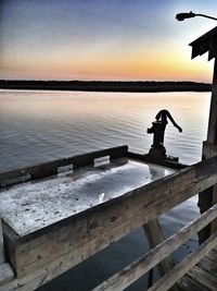 Silhouette of pier on calm lake at sunset