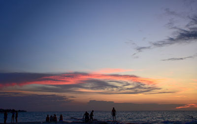 Silhouette people on beach against sky during sunset