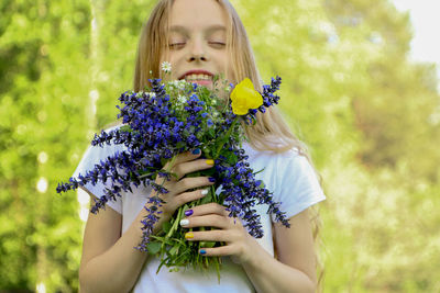Cute girl holding purple flowering plant
