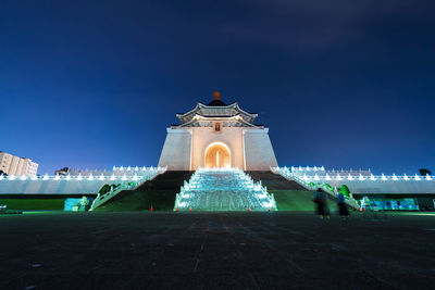 Illuminated building against blue sky at night