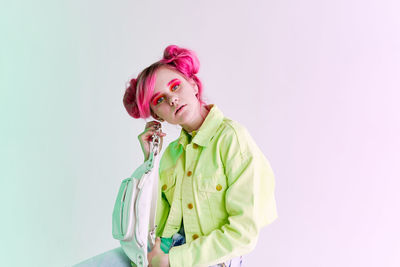 Portrait of young woman standing against white background