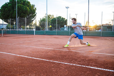 Full length of young man playing tennis on field