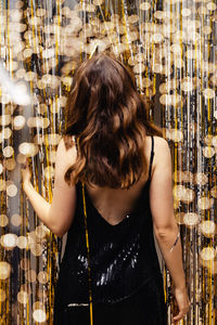 Woman dancing on new year party, festive decor and blurred lights, view from the back