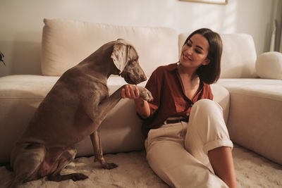 Side view of young woman with dog on bed at home