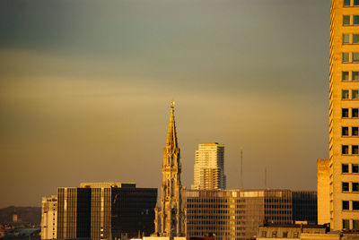 Modern buildings in city against sky during sunset