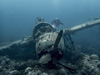Scuba diver swimming by abandoned airplane in sea