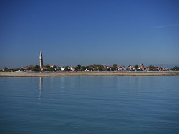 City at waterfront against blue sky