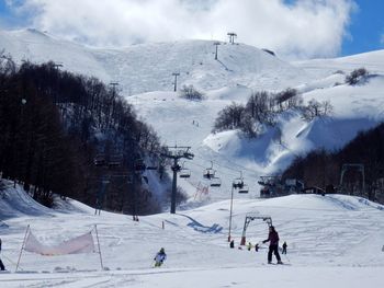 People skiing on snow covered mountains against sky