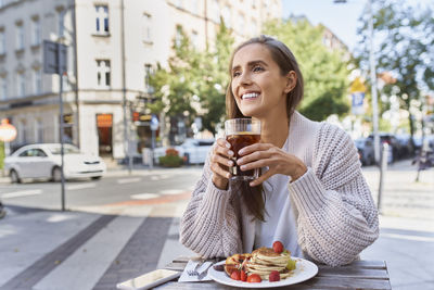 Portrait of a smiling young woman drinking coffee in city