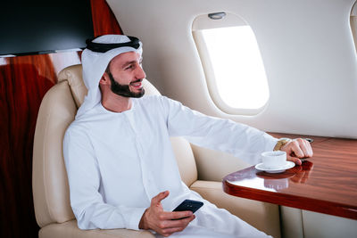 Smiling businessman traveling in corporate jet