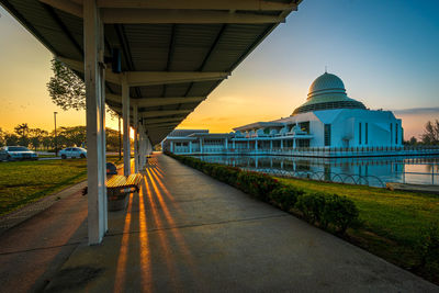 Footpath amidst buildings against sky during sunset