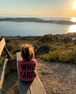 Rear view of woman looking at sea against sky during sunset