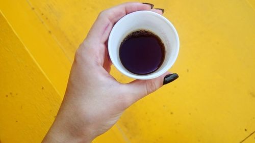 High angle view of hand holding coffee cup